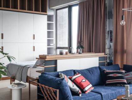 studio moderne avec un canapé convertible, une table basse avec des rangements intégrés et une bibliothèque suspendue