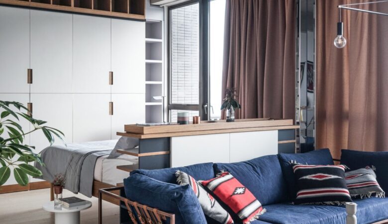 studio moderne avec un canapé convertible, une table basse avec des rangements intégrés et une bibliothèque suspendue