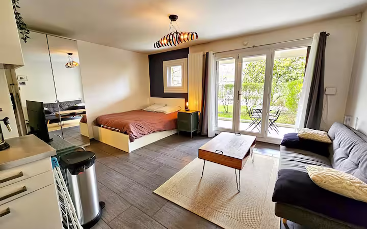 studio moderne bien agencé, où l’on peut voir un coin salon et un coin chambre délimités par un joli tapis, des meubles multifonctionnels comme un canapé-lit ou une table extensible