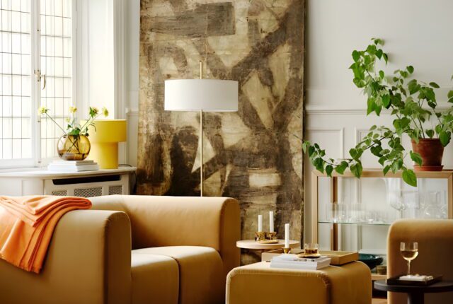 Un salon lumineux, mêlant un fauteuil en velours moutarde, un buffet scandinave vintage, une lampe champignon, et quelques plantes vertes.