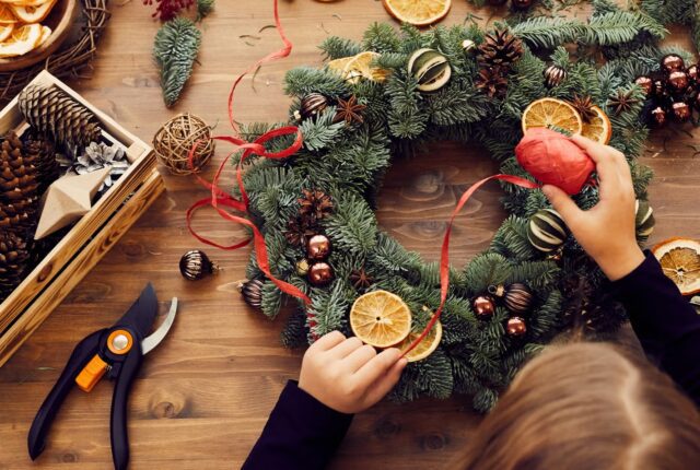 Une photo chaleureuse d’une couronne fait maison, des photophores scintillants et quelques décorations DIY éparpillées