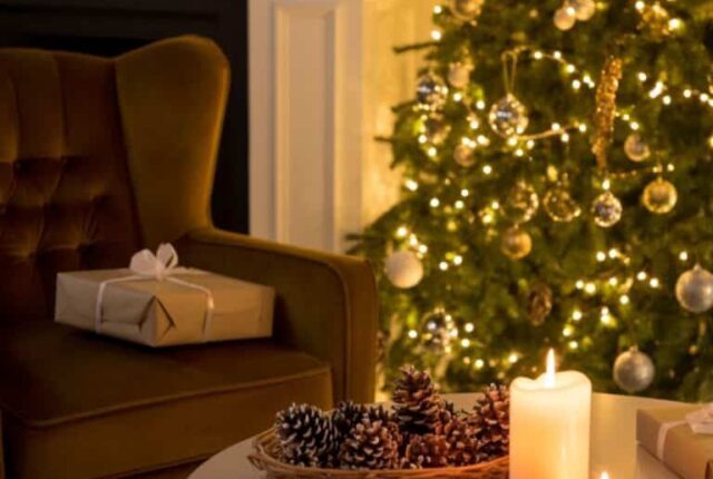 Un salon cosy de Noël avec un sapin décoré de guirlandes naturelles, boules en verre remplies de pommes de pin, des bougies LED sur la table basse